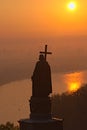 Silhouette of the Monument of Saint Vladimir Volodymyr the Great during sunrise. Morning thick fog and orange sky.