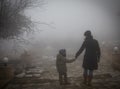 Silhouette of a mother and a child holding hands and walking towards fog mist
