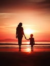 Silhouette of a mother and daughter holding hands on the beach at sunset Royalty Free Stock Photo