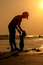 Silhouette of mother with her toddler playing on the beach