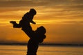 Silhouette of mother lifting child during sunset