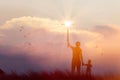 Silhouette of mother and son christian prayers raising cross while praying to the Jesus on sunset background Royalty Free Stock Photo