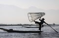 Silhouette of mountain range and traditional burmese fisherman balancing on his boat in the dawn on Inle Lake, Myanmar