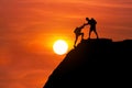 Silhouette Mountaineer Gives Helping Hand His Friend To Climb High Cliff Mountain Together.
