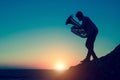 Silhouette of musician playing the tuba on rocky sea coast during amazing sunset. Royalty Free Stock Photo