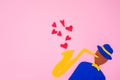 Silhouette of a musician with a saxophone on a pink background, cutted out of felt. International Jazz Day. Copy space