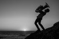 Silhouette of a musician with a trumpet on the seashore. Black and white photo.