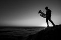 Silhouette of a musician with a tuba on the seashore. Black and white photo.