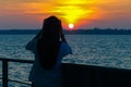 Silhouette of muslim woman taking photo with smart phone camera enjoying sunset scenery at Labuan island,Malaysia. Smart phone cam Royalty Free Stock Photo