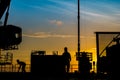 Silhouette of oil and gas wellhead platform and well service worker while working to perforation production tubing gas reservoir.