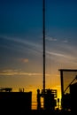 Silhouette of oil and gas wellhead platform and well service worker while working to perforation production tubing gas reservoir.