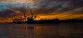 Silhouette of an oil tanker at sunset. Container port in the backgroundSilhouette of an oil tanker at sunset. Container port in th