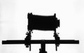 Silhouette of old bellows camera on tripod, horizontal white background, Royalty Free Stock Photo