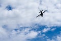 Silhouette of an old four propeller airplane against a backdrop of white clouds and blue sky