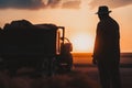 silhouette of old man standing around a trailer in a field of wheat after harvesting at sunset, Generative AI Royalty Free Stock Photo