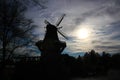 Silhouette of an old windmill made of wood . The sun in background