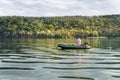 Silhouette one alone mature man sitting in green inflatable rubber motor boat and enjoy relax fishing on foggy overcast Royalty Free Stock Photo