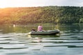 Silhouette one alone mature man sitting in green inflatable rubber motor boat and enjoy relax fishing on foggy overcast morning Royalty Free Stock Photo