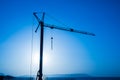 Silhouette, outline of the crane on the construction site against the blue sky and the sea. Details of the building, ribbed walls