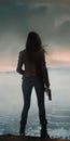 silhouette of a woman holding a gun and standing on a cliff Royalty Free Stock Photo