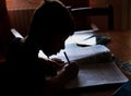 Silhouette over bright window light background of Children on his school homework