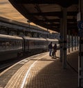 A silhouette of a pair of passengers standing on a railway platform with a train in the background Royalty Free Stock Photo