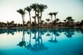 Silhouette palm tree with umbrella chair pool in luxury hotel resort at sunrise times. Summer vocation Royalty Free Stock Photo