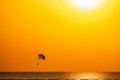 Silhouette of a parachute and a skydiver against the background of a bright burning sunset over the sea