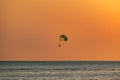 Silhouette of a parachute and a skydiver against the background of a bright burning sunset over the sea