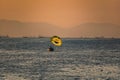 Silhouette of a parachute and a skydiver against the background of a bright burning sunset over the sea