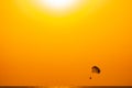 Silhouette of a parachute and a skydiver against the background of a bright burning sunset over the sea