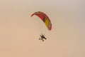 Silhouette of the Paramotor gliding and flying In the air through soft sunlight sky Royalty Free Stock Photo