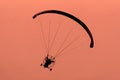 Silhouette of the Paramotor gliding and flying In the air through soft sunlight sky Royalty Free Stock Photo