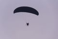 Silhouette of the Paramotor gliding and flying In the air through soft sunlight sky Royalty Free Stock Photo