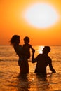 Silhouette of Parents with child in sea on sunset