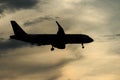 Silhouette passenger airplane flying away in to sky high altitude on sunset