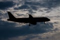 Silhouette passenger airplane flying away in to sky high altitude on sunset