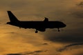 Silhouette passenger airplane flying away in to sky high altitude on sunset