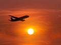 Silhouette passenger airplane flying away in to sky on sunset