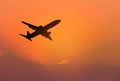 Silhouette passenger airplane flying away in to sky during sunset