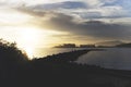 Silhouette of a pathway on the water with buildings in the distance under a cloudy sky Royalty Free Stock Photo