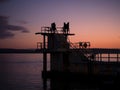 Silhouette of people on Blackrock diving tower at sunset. Salthill, Galway city. Popular sport and tourist landmark with stunning