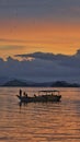 A silhouette of people on the boat with thousands bats flying upon them in Nusa Tenggara Timur, Indonesia