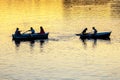 silhouette of people in boats with oars on the evening river