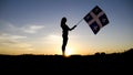 Silhouette of people with flag on mountain top .