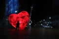 Silhouette of people in front of a red lighted heart