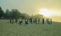 Silhouette of people group practicing yoga on beach at sunrise