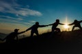 Silhouette of people helping each other hand by hand