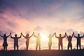 Silhouette of people holding hands against sunset background, concept of peace and victory