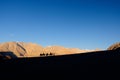 The silhouette of people riding a camel in the desert.